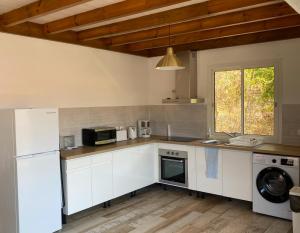 豪特尔Haut de villa Taalia的厨房配有白色橱柜、洗衣机和烘干机