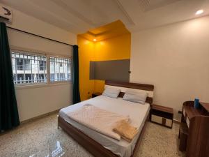 科纳克里SMB-gn RÉSIDENCE LAMBANDJI的一间卧室设有一张黄色墙壁和窗户的床