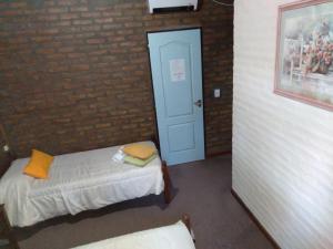 梅洛Hotel Altos del Rincon的一间设有两张床和砖墙的房间