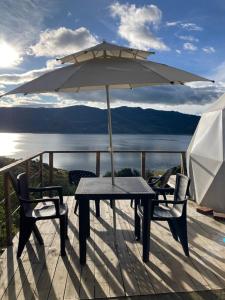 瓜塔维塔Glamping Vista Lago Guatavita的甲板上配有桌椅和遮阳伞