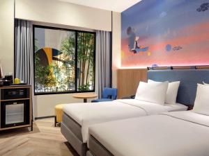 三宝垄ibis Styles Semarang Simpang Lima的酒店客房设有两张床和窗户。