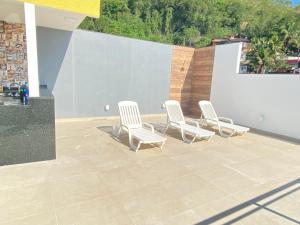 安格拉杜斯雷斯Suítes com Vista para o Mar no Marinas - Mirante do Marinas的四把白色椅子坐在带墙壁的庭院