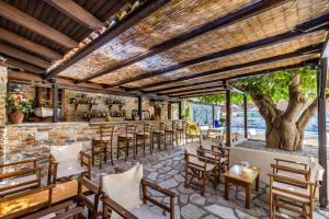 斯科派洛斯Ionia Hotel的酒吧设有木椅、桌子和树