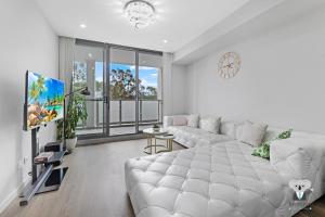 文特沃斯维尔KozyGuru / Wentworthville / Kozy Style 2 Bed 2 Bath APT + Free Parking NWE031A的客厅配有白色沙发和大窗户