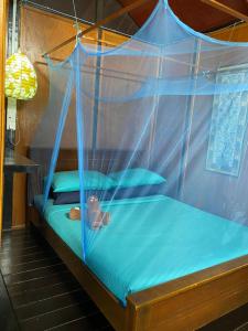 刁曼岛The Station Tioman的一间卧室配有一张带蓝色枕头的天蓬床
