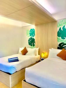 八打雁The Henry Resort Taramindu Laiya的配有白色床单的酒店客房内的两张床