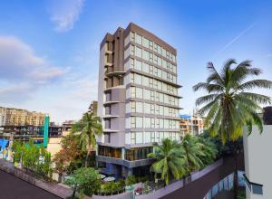 孟买Lemon Tree Hotel, Kalina, Mumbai的一座高大的建筑,前面有棕榈树