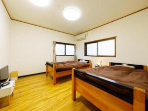 嬉野市Ureshino Onsen Kotobukiya的一间卧室配有两张床、一张桌子和一台电视。