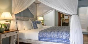 科伦坡玛尼帕西度假酒店的一间卧室配有一张天蓬床、一张桌子和灯。