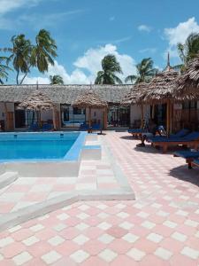 帕杰Amani Hotel Paje的一个带桌子和稻草遮阳伞的游泳池的度假酒店