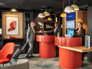 鲁瓦西昂法兰西诺富特套房酒店 - 巴黎戴高乐机场维勒班的三人站在大厅的柜台