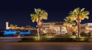 利雅德Radisson Hotel Riyadh Airport的一座棕榈树度假村,位于一座建筑前