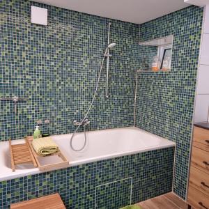 沃尔夫斯堡Gästewohnung Detmerode的浴室铺有绿色瓷砖,配有浴缸。