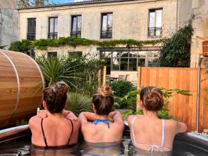 拉罗谢尔Escale Rochelaise, gîte urbain avec SPA bain nordique et sauna tonneau的三个女孩坐在后院的热水浴缸里