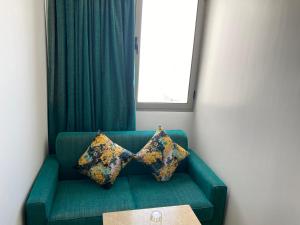 卡萨布兰卡蓝色海岸酒店 的绿色沙发,上面有两个枕头,窗户
