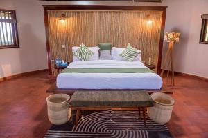 AruaTilenga Safari Lodge的一间卧室配有一张大床和木制床头板
