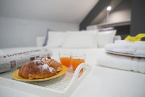 萨莱诺B&B Milleduecento Luxury Room的盘子上放着糕点和一杯橙汁