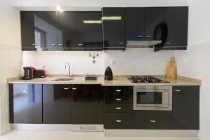 里斯本Otília Apartamentos的厨房配有黑色橱柜和水槽