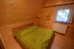 Jaroslavické PasekyMeadow Ranch Holiday Home的木制客房内的一间卧室配有一张绿色的床