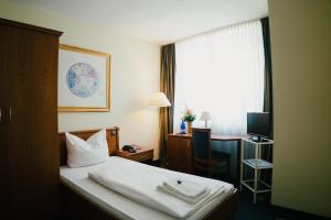 杜塞尔多夫老城圣乔治酒店的配有一张床、一张书桌和一扇窗户的酒店客房