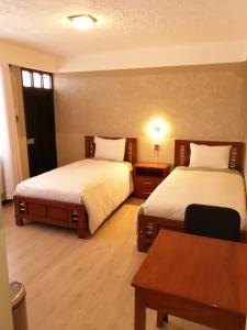 乌尤尼Hotel CESARE的酒店客房设有两张床和一张桌子。