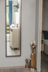 大毛罗什Aranyos Hillside的墙上的镜子,前面有一只猫雕像