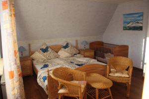 多尔努姆Ferienhaus Brigitte的一间卧室配有一张床、椅子和一张婴儿床