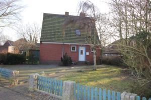 多尔努姆Ferienhaus Brigitte的一座红色的房子,屋顶绿化,有蓝色的栅栏