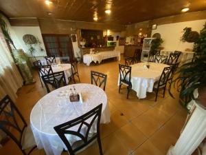 克拉约瓦Pensiunea Luisa的用餐室配有桌椅和白色桌布