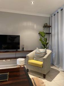 普利登堡湾Lux apartment Plett的客厅配有椅子和电视