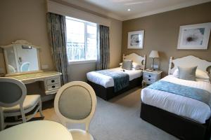 基拉尼International Hotel Killarney的酒店客房带两张床和一张桌子以及椅子。