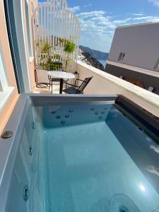 伊亚ArmonOia Suites的一个带桌椅的阳台的小型游泳池