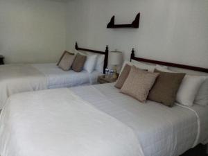 瓜达拉哈拉波萨达圣塔菲酒店的配有白色床单的酒店客房内的两张床