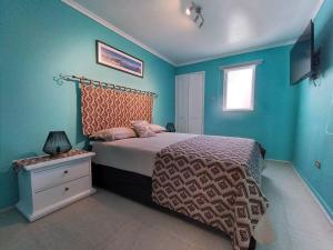 圣地亚哥Bello y cómodo departamento a minutos del centro的一间卧室配有一张蓝色墙壁的床和一扇窗户