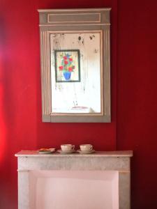 屈屈龙la dame jeanne的壁炉上方的红色墙面,上面有镜子