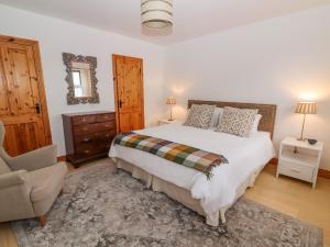 恩尼斯Cherry Blossom Cottage的一间卧室配有一张大床和一把椅子
