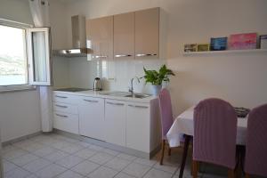 帕格Apartments Pavicic Marija的厨房配有白色橱柜和一张带紫色椅子的桌子