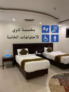 达曼Arrawiya Alzahabia Hotel的墙上有标牌的房间的两张床