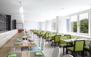 雅加达珊迪卡卡拉巴加丁酒店的用餐室配有长桌子和绿色椅子
