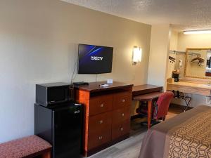 AmoryBriarwood Inn的酒店客房配有一张床和一张书桌及一台电视