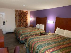 AmoryBriarwood Inn的酒店客房设有两张床和紫色墙壁。