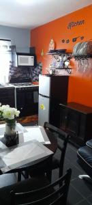 曼德维尔Tashari-dae Inn king suite的带橙色墙壁和桌子的厨房以及带冰箱的厨房。