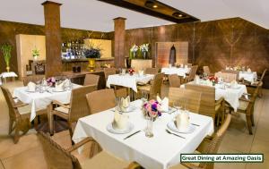 北芭堤雅泰花园度假酒店的餐厅设有白色的桌椅和鲜花