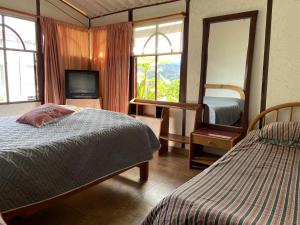 圣弗朗西斯科El Rinconcito Feliz的一间卧室设有两张床、一台电视和窗户。