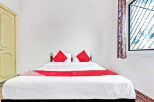 ChikalthānOYO Shree Balaji Lodging的一间卧室配有一张带红色枕头的大床