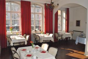 海德堡玉米市场酒店的餐厅设有白色的桌子和红色的窗帘和窗户。
