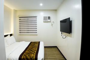 卡加盐德奥罗PRIMELUXE HOTEL的一间卧室配有一张床和一台平面电视