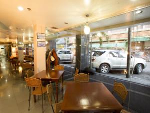 伊洛伊洛港口镇酒店的餐厅设有桌椅,窗户上设有汽车