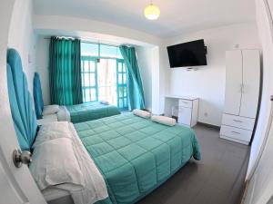 帕拉卡斯AQUAMARINE PARACAS Beach Hostal的一间卧室配有绿色的床和电视