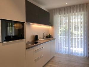 梅拉诺Neu, zentral, sonnig, Garage inklusive的厨房配有白色橱柜、水槽和窗户。